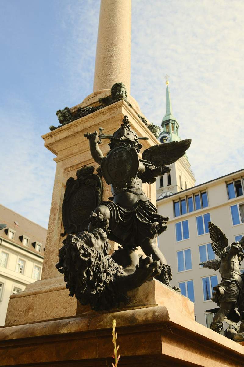 The ornate facade of the Munich town hall, with a clock and rows of statues.