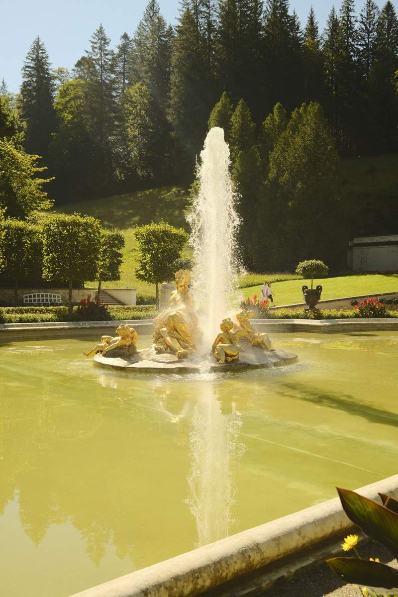 The fountain terrace in front of Linderhof Palace, with golden statues along the water.