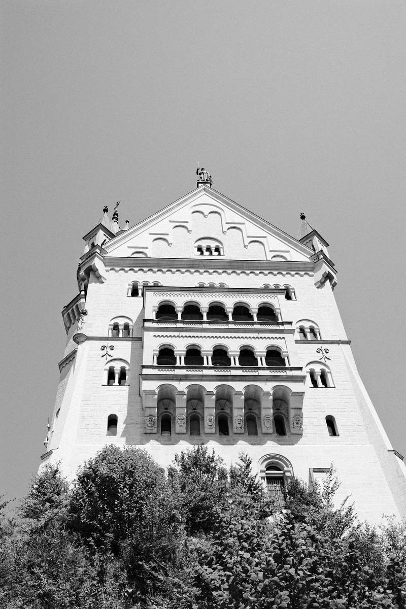 Neuschwanstein Castle on a rocky hill, seen from across a green valley.