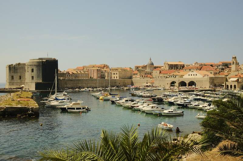 Dubrovnik's city walls dropping toward the sea, with red roofs inside the old town.