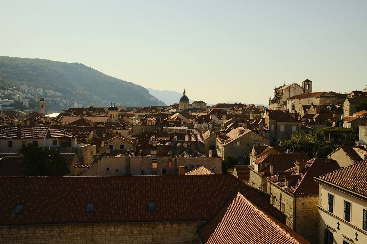 Dubrovnik's old town at golden hour, red roofs packed down to the harbor and an island offshore.